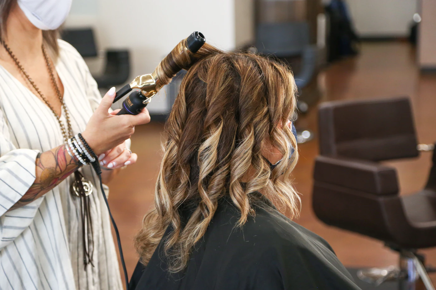 Hairstylist creating a polished hairstyle before applying finishing L’Oréal Paris Elnett Satin Hairspray
